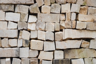 A tightly stacked arrangement of large rectangular stones. The stones vary in size and color, creating an uneven texture across the surface.