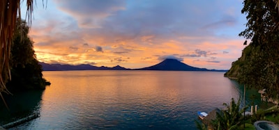 A sunset view over Lago de Coatepeque with a cozy lakeside restaurant glowing warmly.