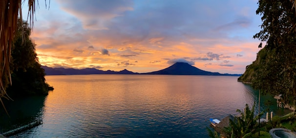 Sunset view over Lago de Coatepeque with a cozy lakeside restaurant glowing warmly.