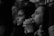 Two individuals appear focused and contemplative, sitting side by side in a dimly lit environment. Their hands are clasped together, resting near their faces, and their expressions suggest deep concentration or concern.