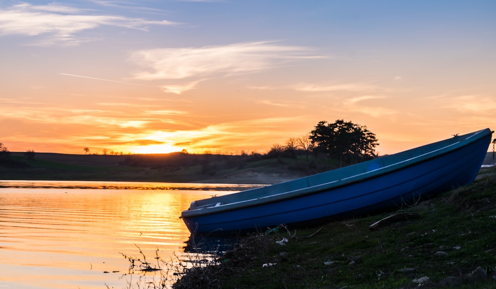blue boat on lake during sunset