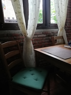 An inviting breakfast nook bathed in natural light with sage green cushions and a creamy white table set for a meal.