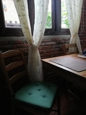 Bright breakfast nook with rustic wooden table set against a backdrop of forest green walls.