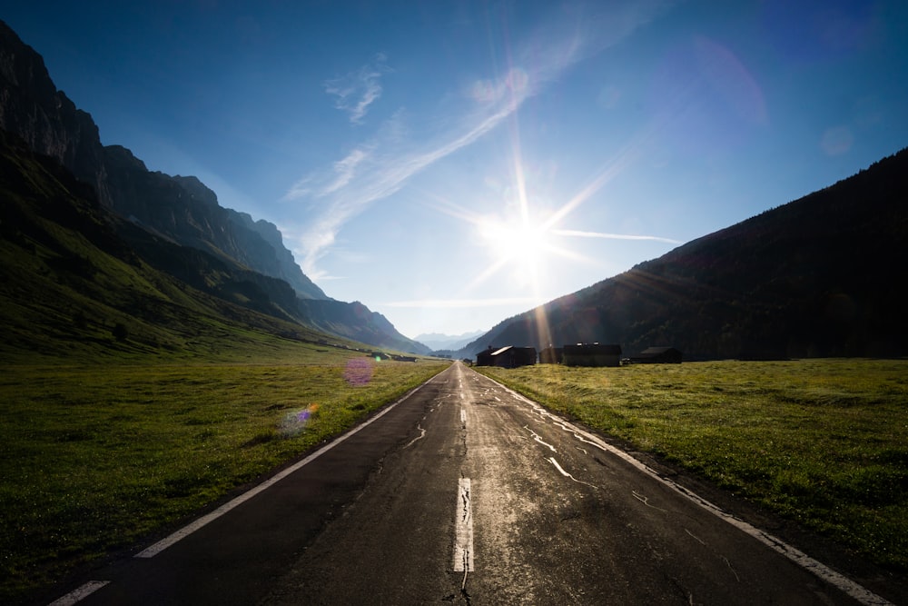 gray asphalt road between green grass field during daytime