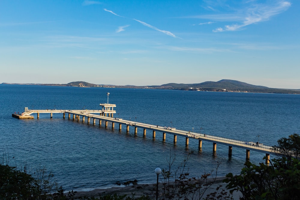 Muelle de madera blanco y marrón en el mar bajo el cielo azul durante el día