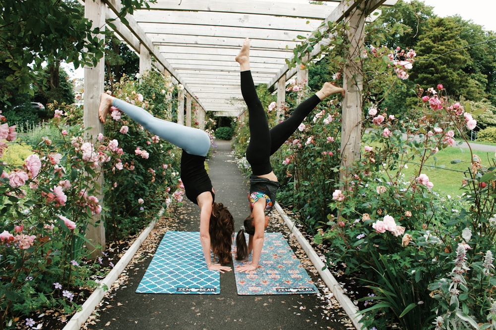 woman in black leggings and black tank top jumping on brown concrete pathway