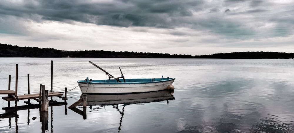 bateau blanc et bleu sur l’eau sous un ciel nuageux pendant la journée