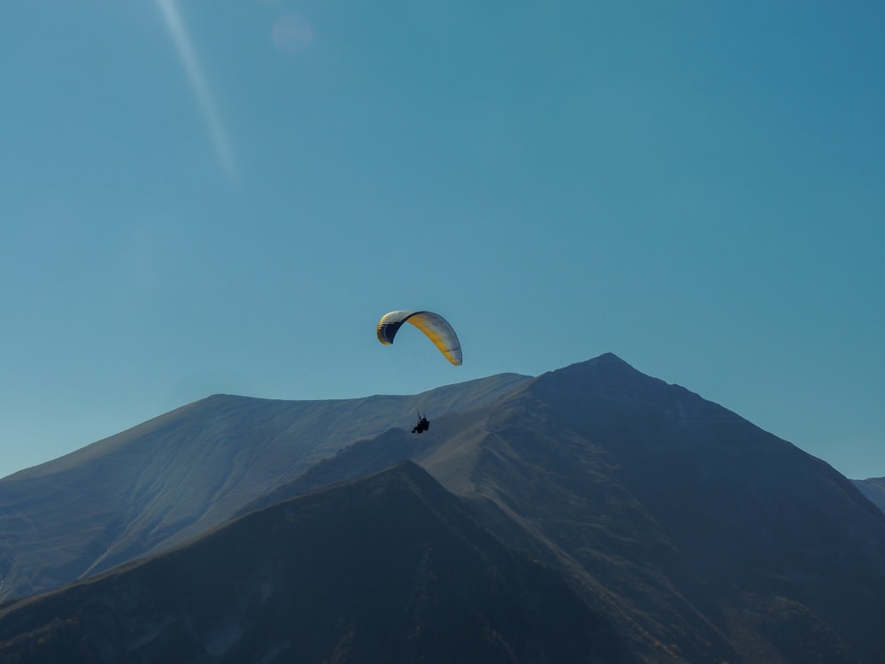 personne en parachute jaune au-dessus de la montagne pendant la journée