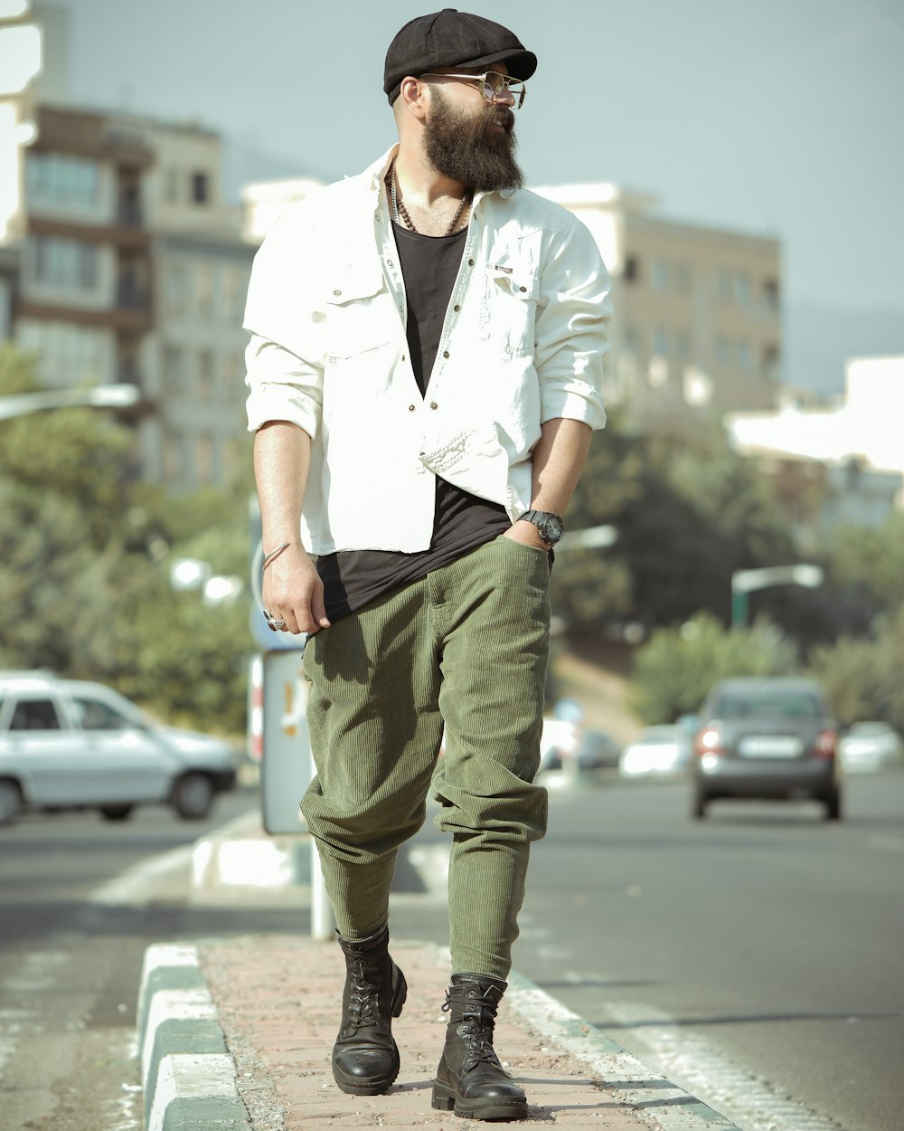 man in white button up shirt and green pants standing on road during daytime