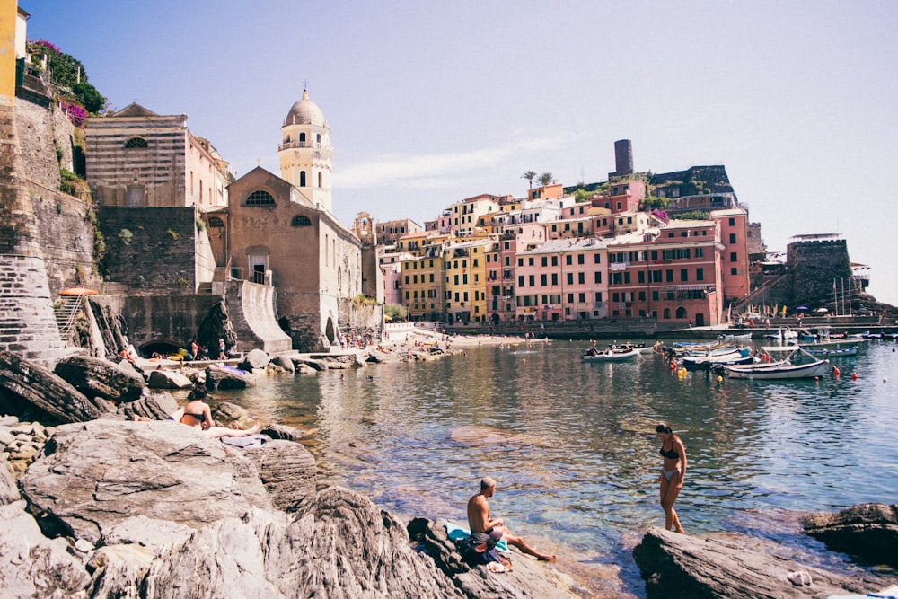 people sitting on rock near body of water during daytime