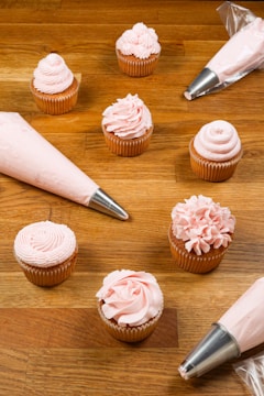 Close-up of pastel pink cake decorating tools arranged neatly on a soft fabric background.