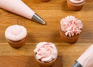 pink and white cupcakes on brown wooden tray