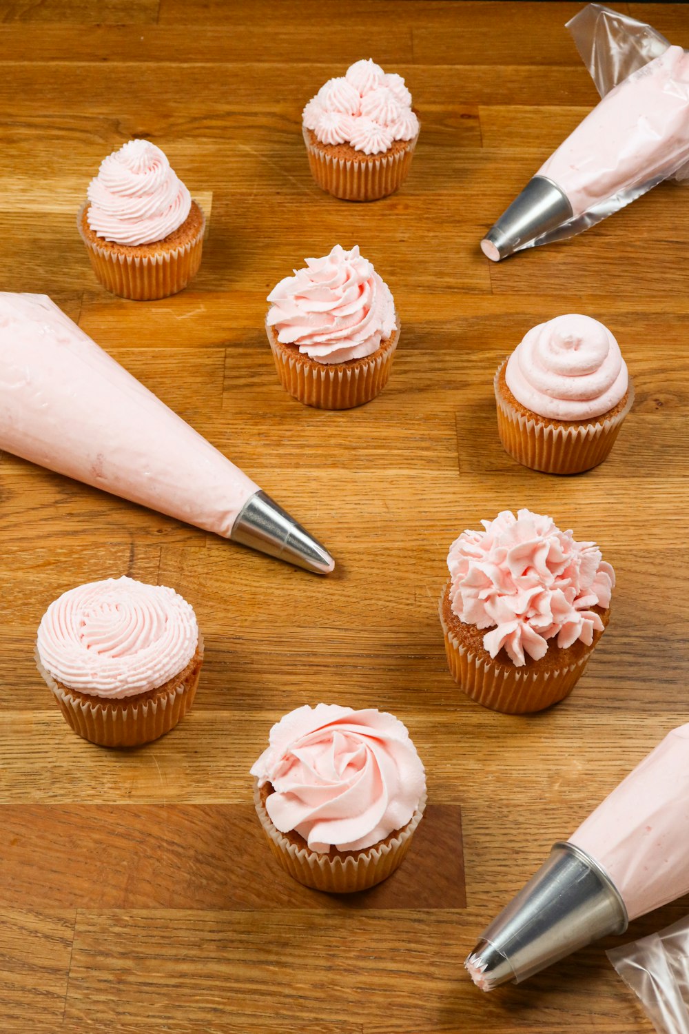 pink and white cupcakes on brown wooden tray