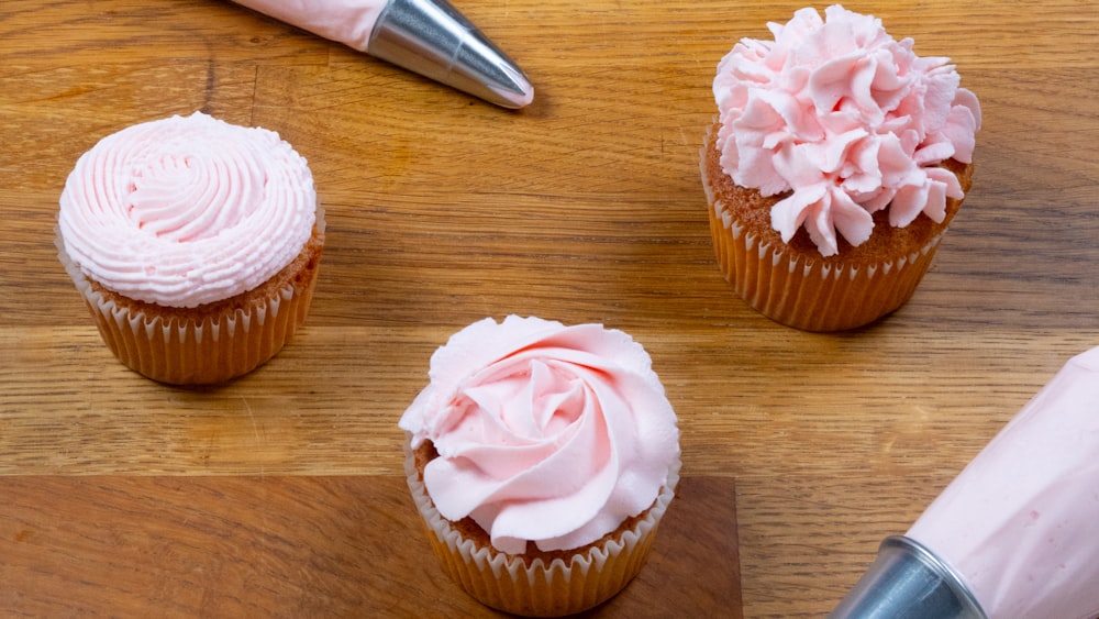cupcake with pink icing on brown wooden table