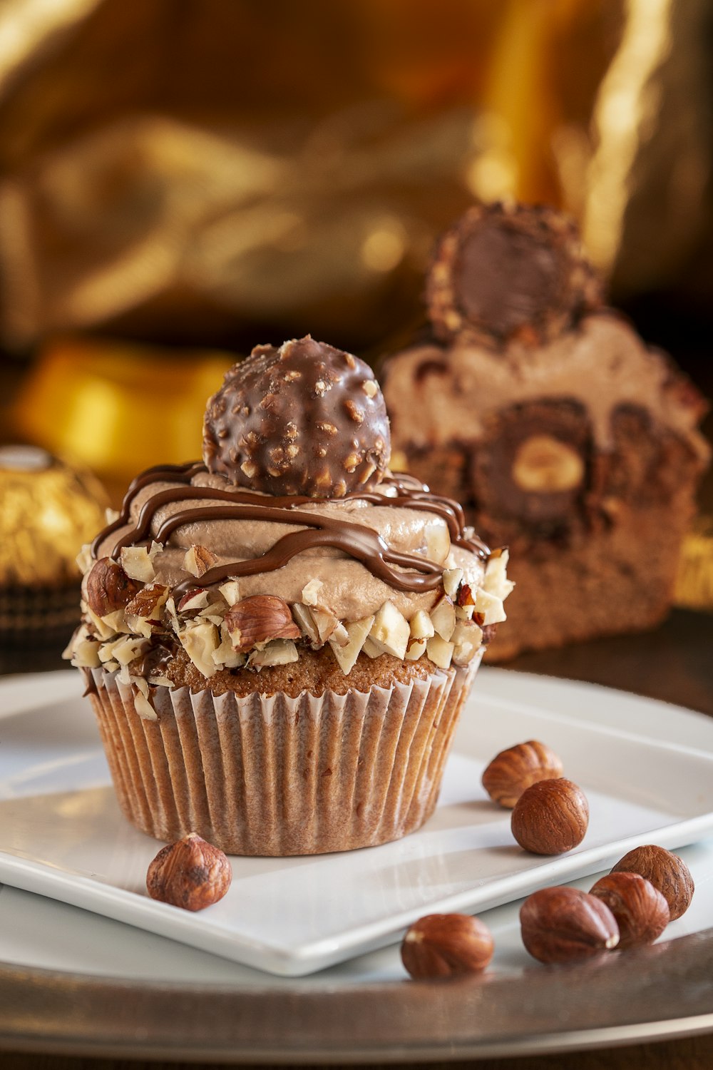 Cupcake de chocolate com cobertura branca em placa de cerâmica branca