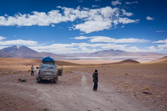 man in black jacket standing beside white car during daytime in Laguna Colorada Bolivia