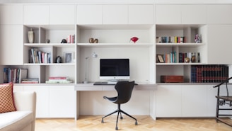 black office rolling chair near white wooden shelf