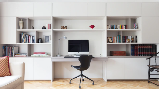 black office rolling chair near white wooden shelf