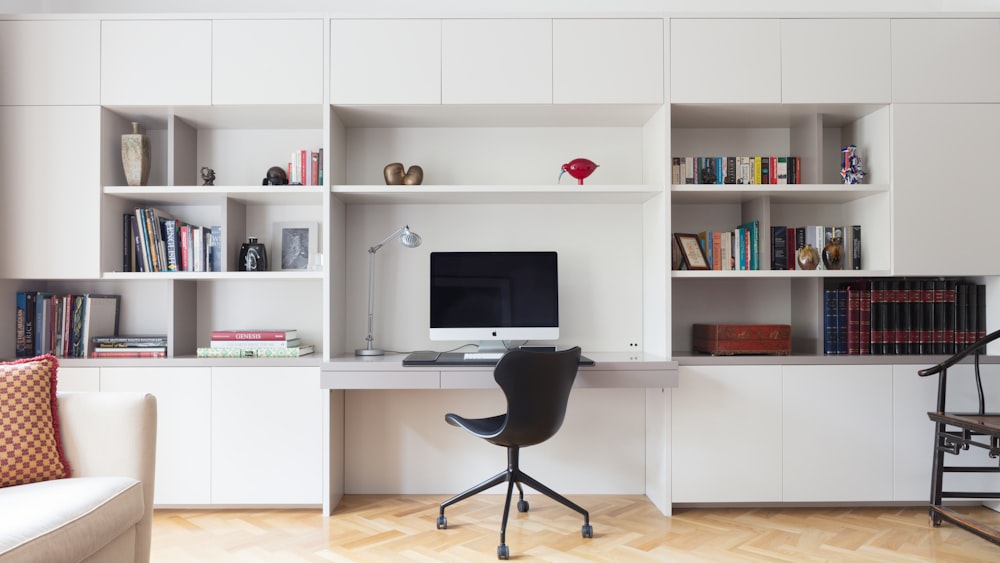 black office rolling chair near white wooden shelf