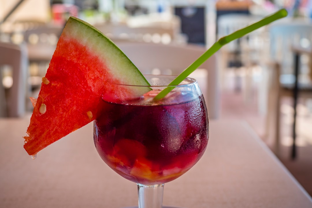 clear wine glass with red liquid and sliced of watermelon