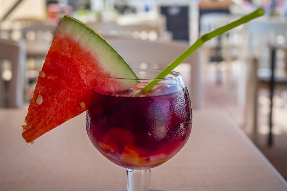 Copa de vino transparente con líquido tinto y rodajas de sandía