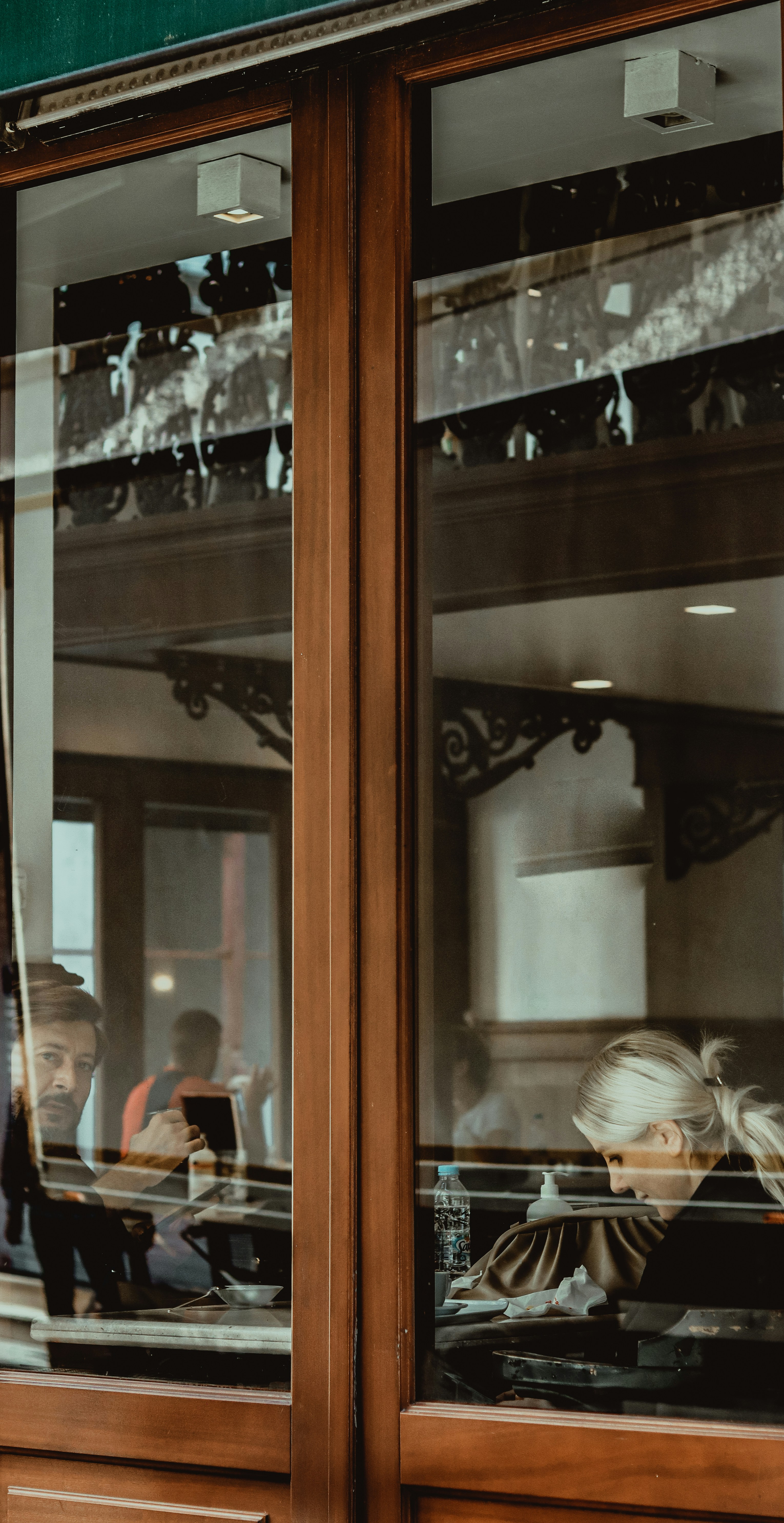 茶色の木製のガラスキャビネットの前の椅子に座る人々