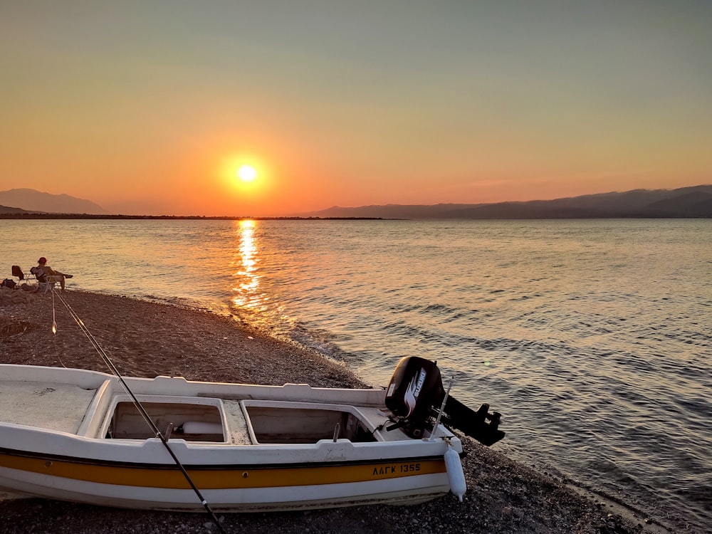 white and brown boat on sea shore during sunset