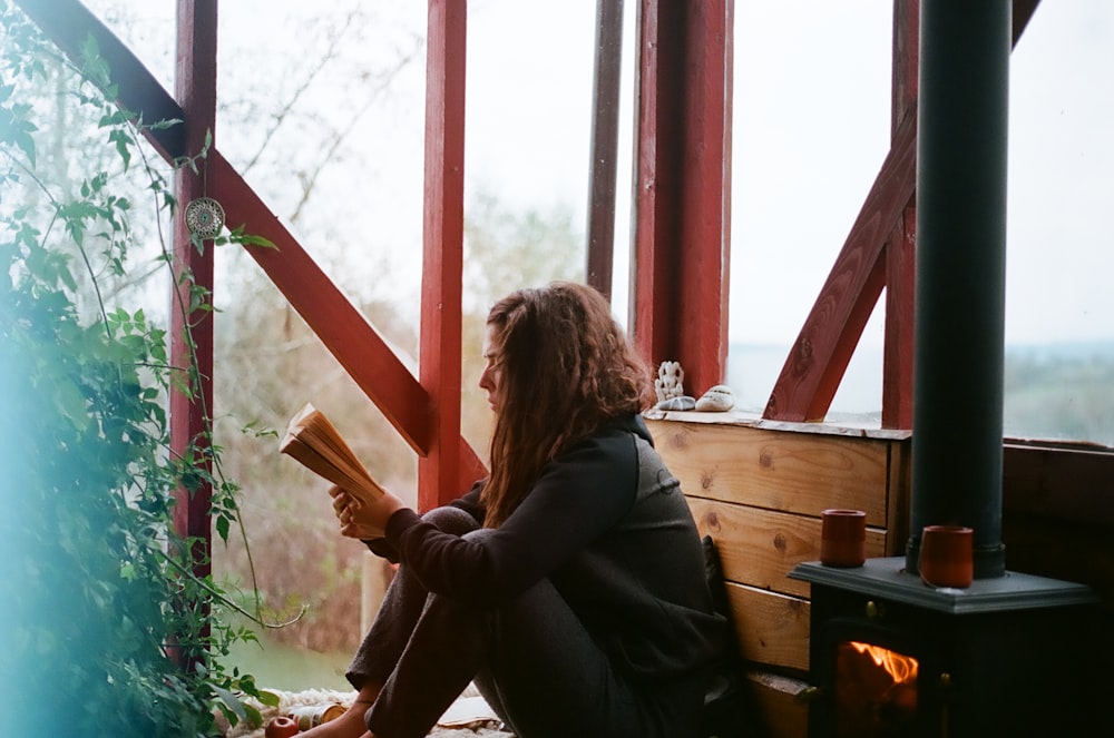 woman in black jacket sitting on brown wooden bench