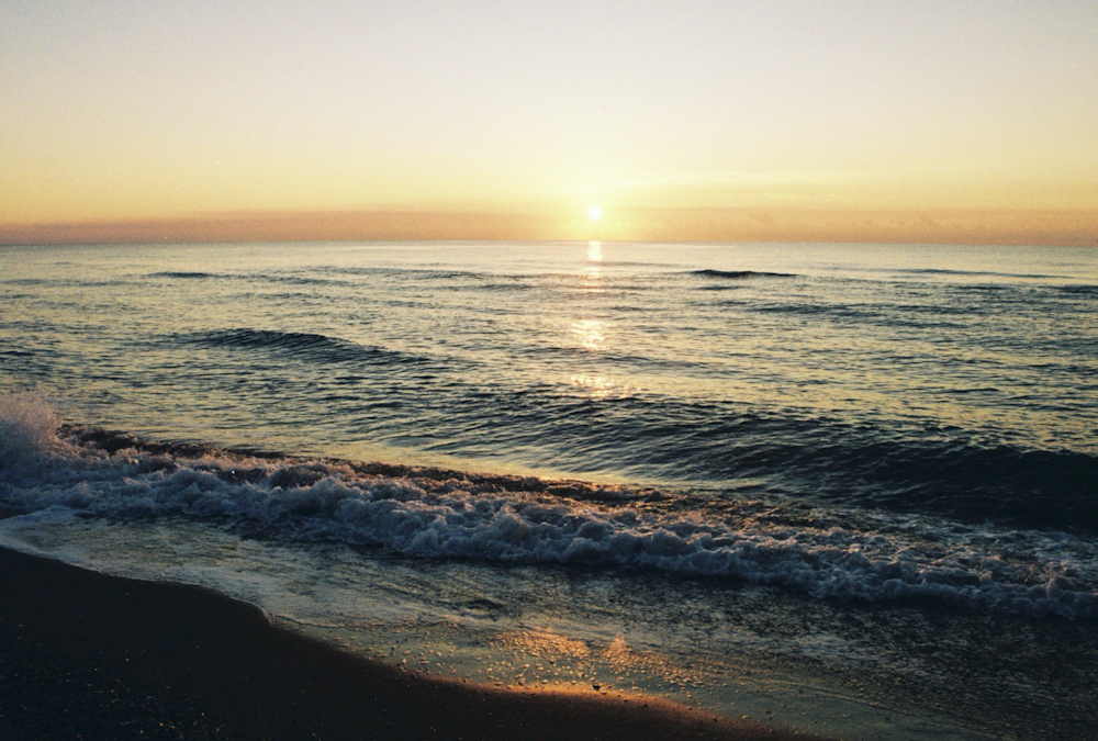 ocean waves crashing on shore during sunset