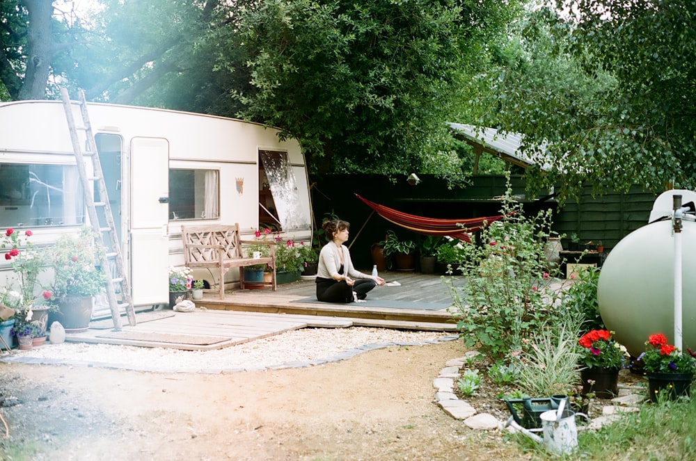 woman in white long sleeve shirt sitting on brown wooden bench near white concrete building during