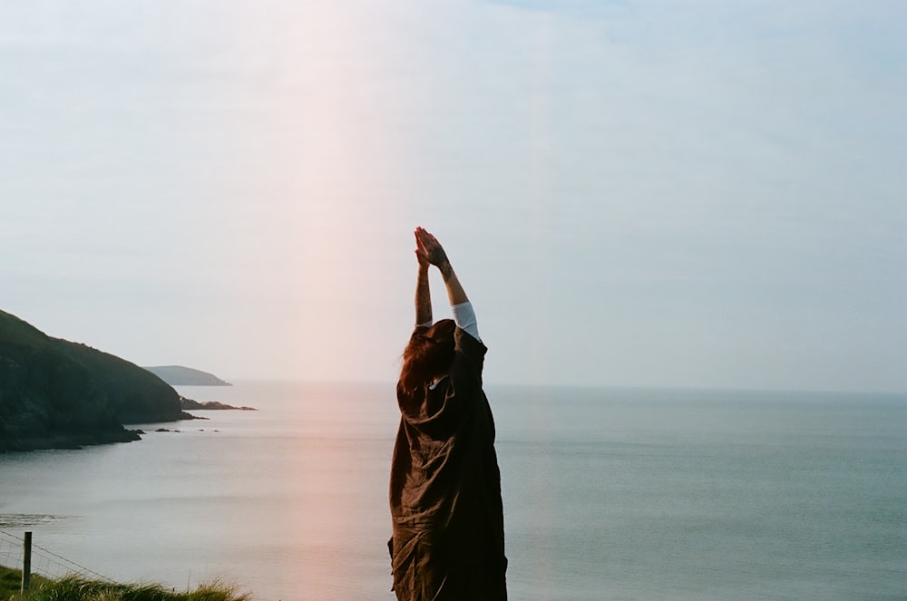 woman in brown hijab standing on green grass field near body of water during daytime