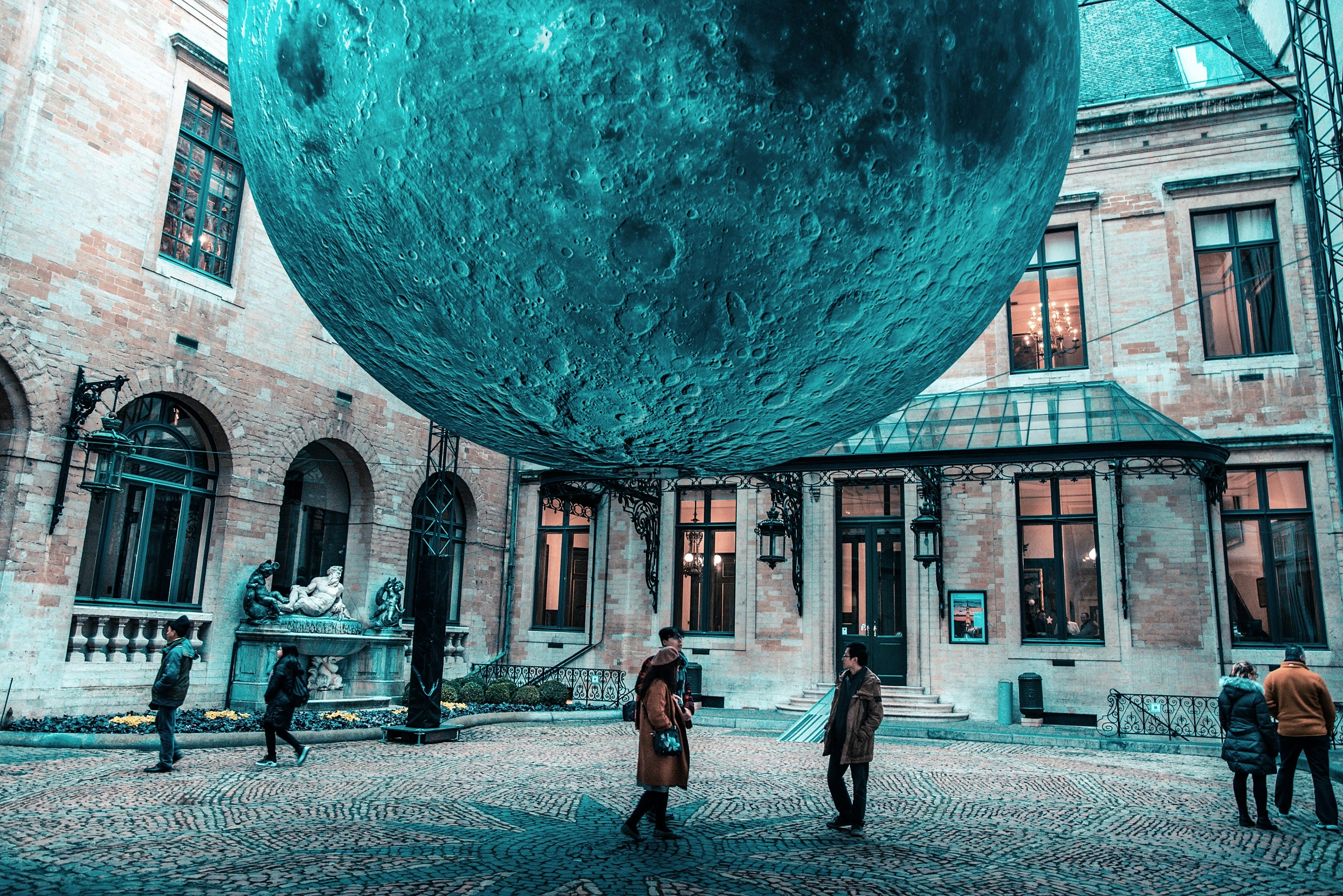 people walking on sidewalk near blue and white moon during daytime