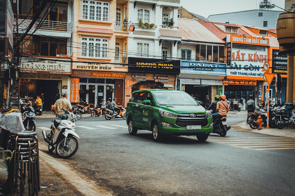 green car parked beside white and brown concrete building during daytime