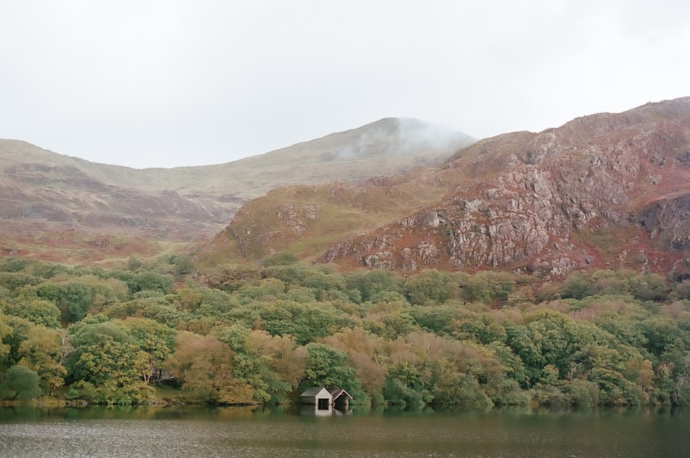 green and brown mountain beside lake during daytime