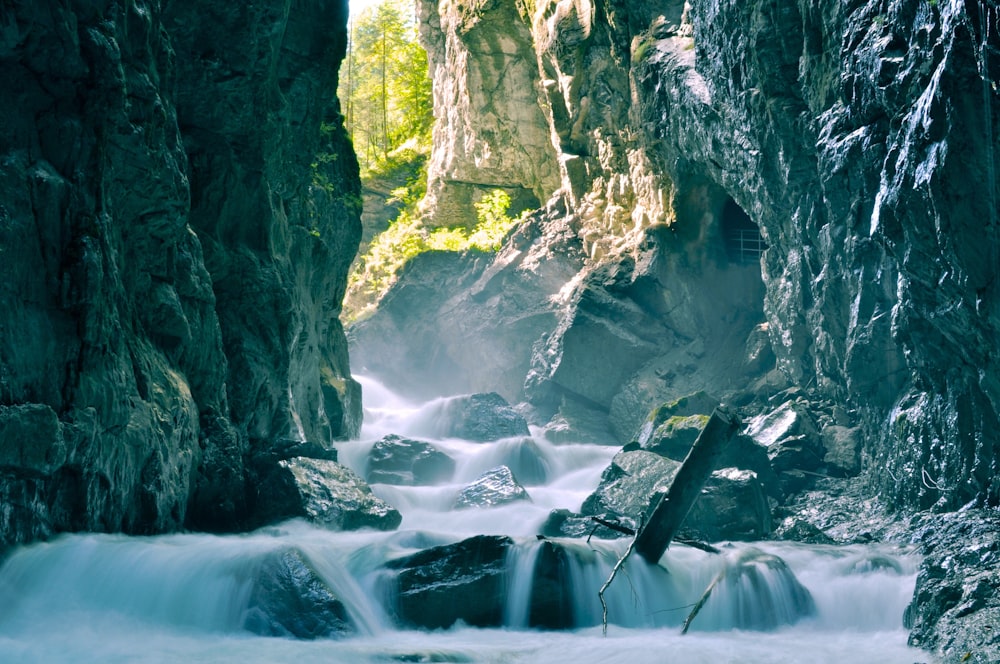 water falls between gray rocky mountain during daytime