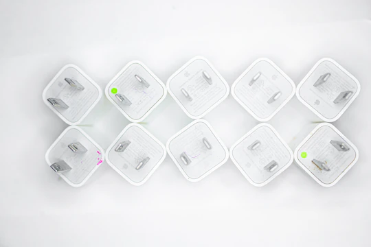 Array of compact power adapters in silver and white, neatly arranged against a dark blue background.