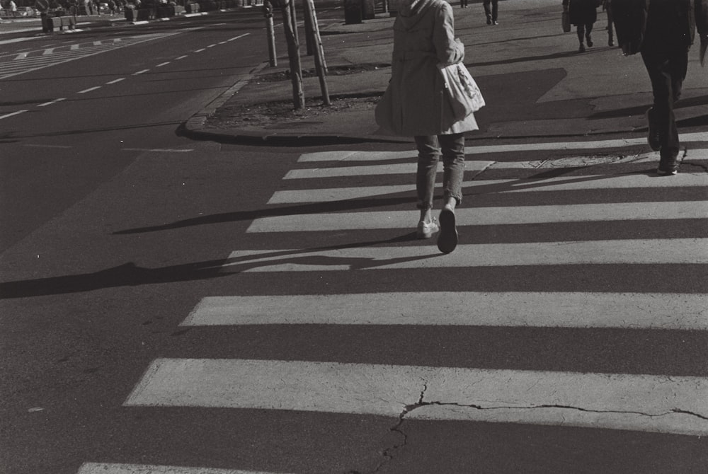 woman in white coat walking on pedestrian lane during daytime