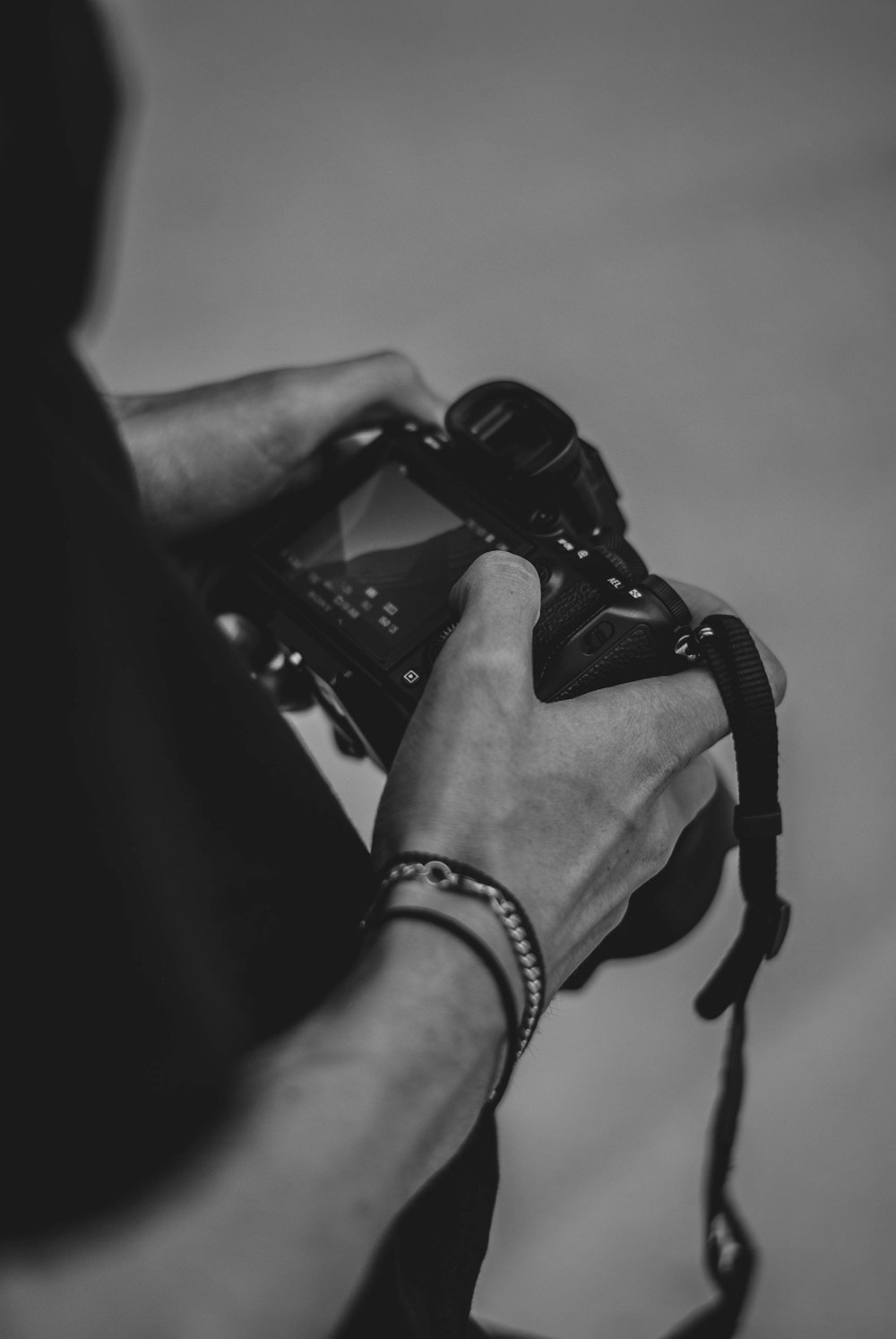 grayscale photo of person wearing black watch and black dslr camera
