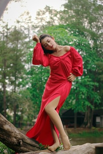 A woman in a red dress posing on a log