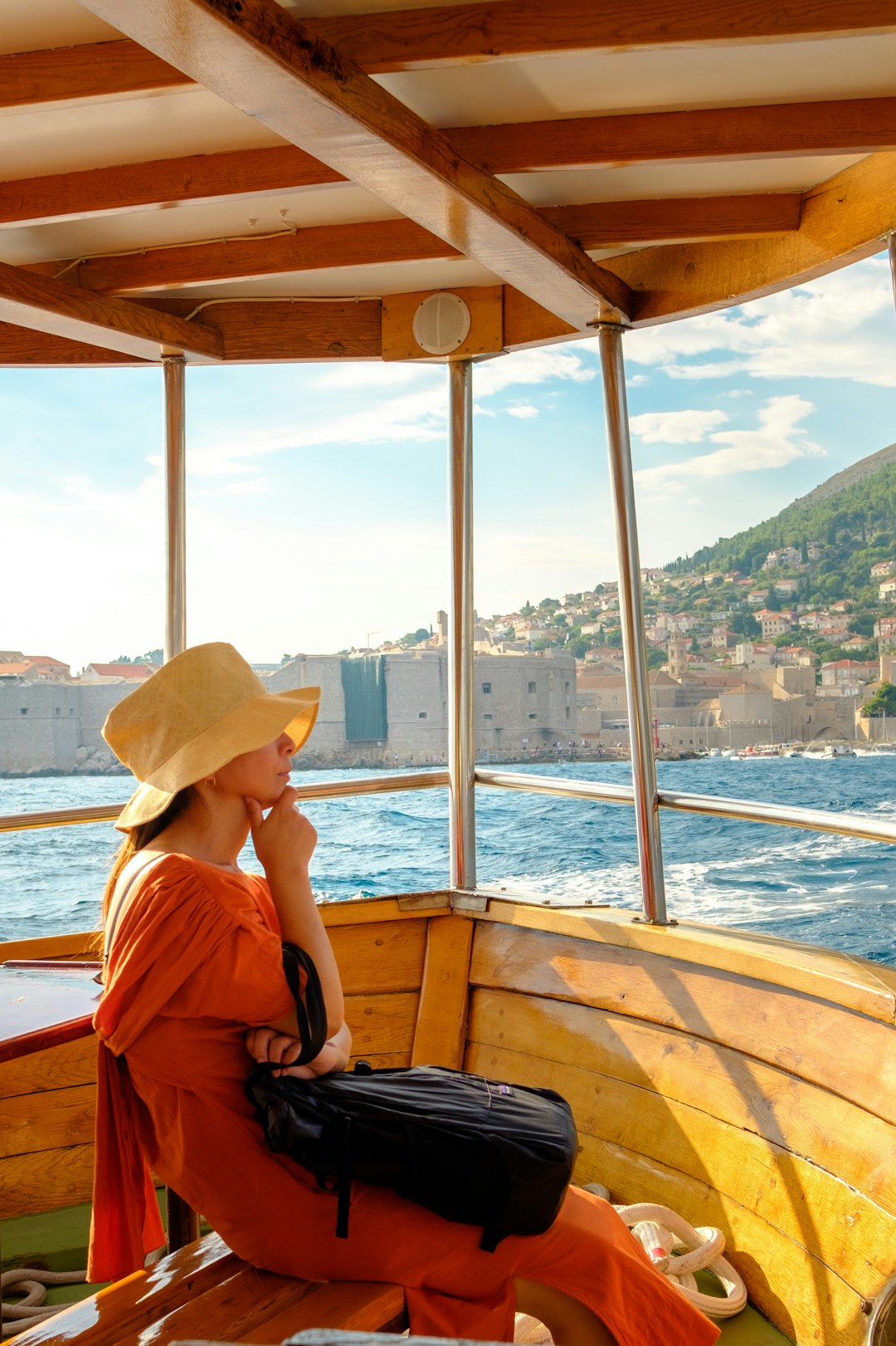 woman in brown sun hat sitting on brown wooden boat during daytime