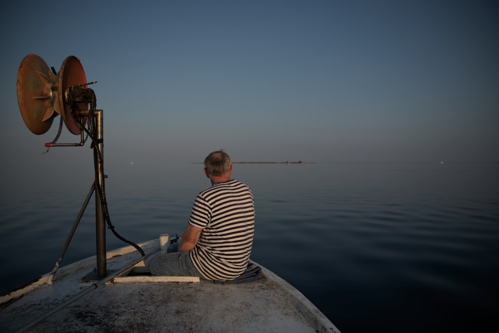 woman in white and black striped shirt sitting on boat during daytime