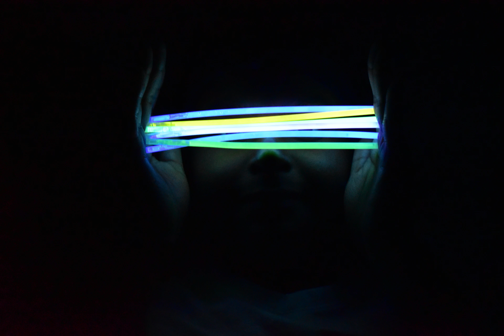 Close-up of colorful wristbands and glow sticks glowing against a dark background, hinting at the excitement of upcoming events.