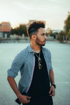A stylish man with well-groomed hair and beard enjoying a sunny day outdoors.