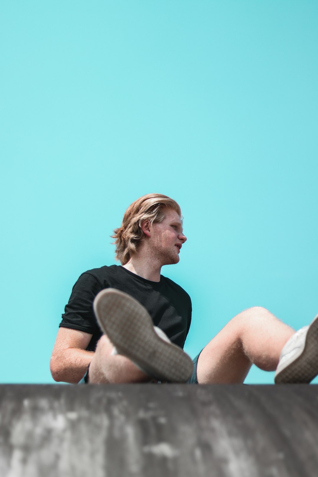 man in black crew neck t-shirt sitting on brown wooden bench