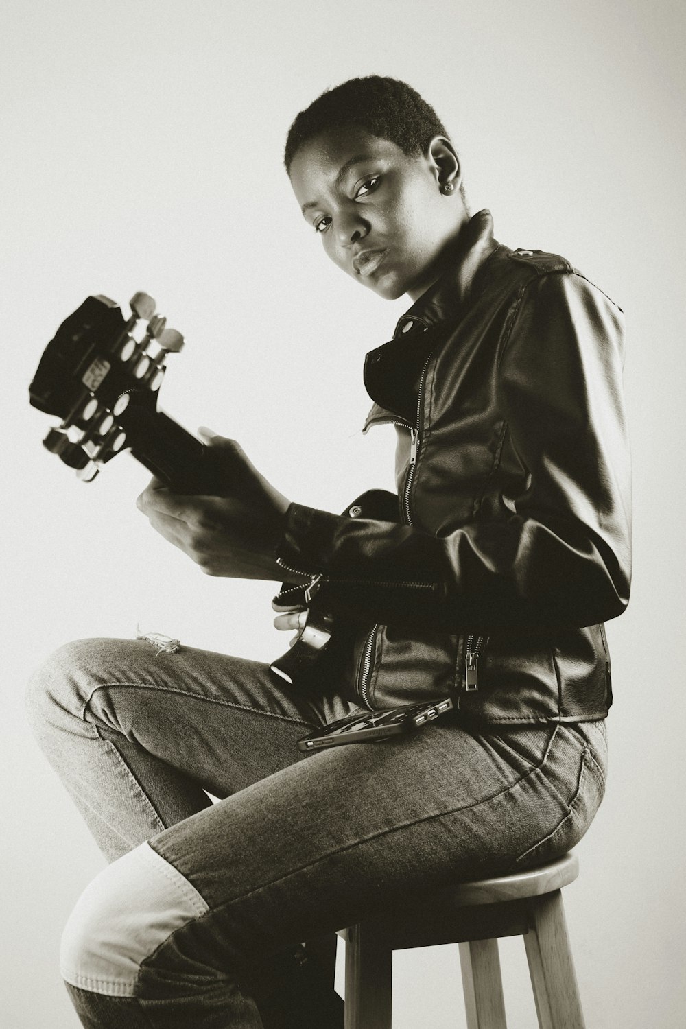 man in black leather jacket and gray denim jeans holding black and white game controller