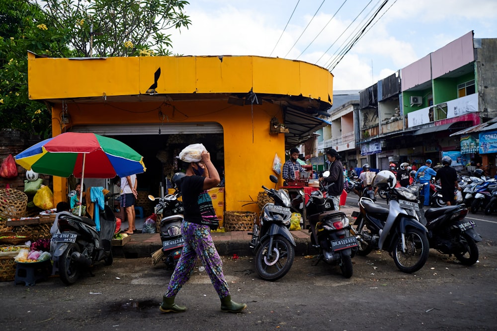 man in black jacket and green pants standing beside motorcycle during daytime