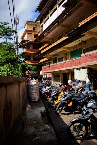 A row of motorcycles ready for rent parked neatly under a bright city sky
