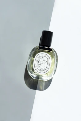 A stylish men's fragrance bottle with subtle shadows on a cream-colored surface.