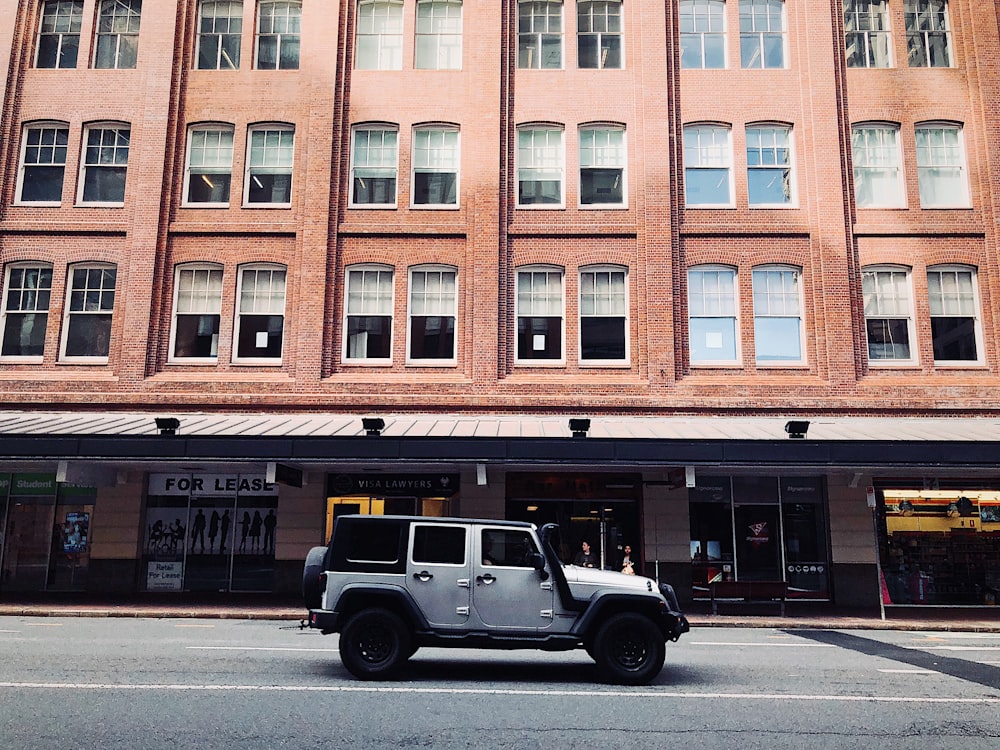 낮 동안 갈색 콘크리트 건물 옆에 주차된 흰색과 검은색 SUV