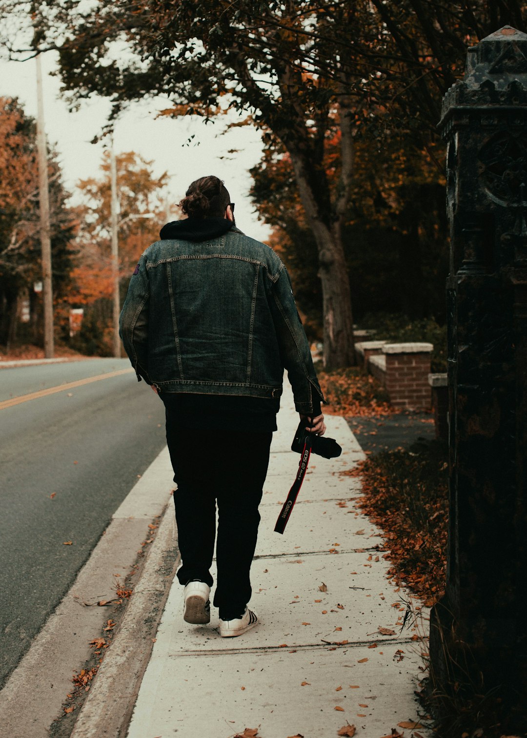 man in black jacket walking on road during daytime
